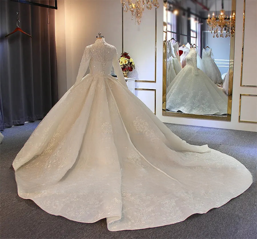 Back view of a modest Muslim bridal gown on a mannequin, highlighting the grand cathedral train and the sophisticated buttoned-back design of the long-sleeved dress.