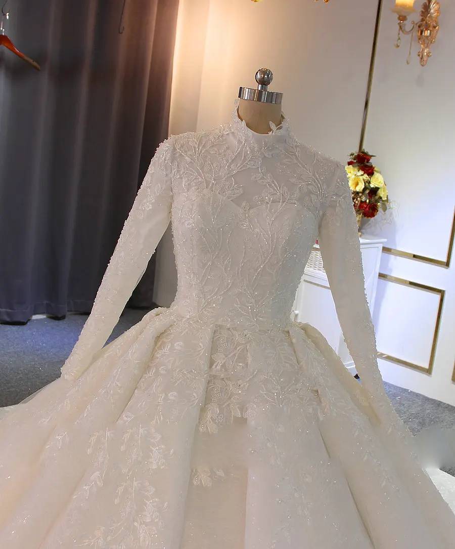 Close-up shot of the bodice and high neckline of a modest Muslim bridal dress, detailing the fine lace craftsmanship and beaded floral embroidery on the full-lined, long-sleeved gown.