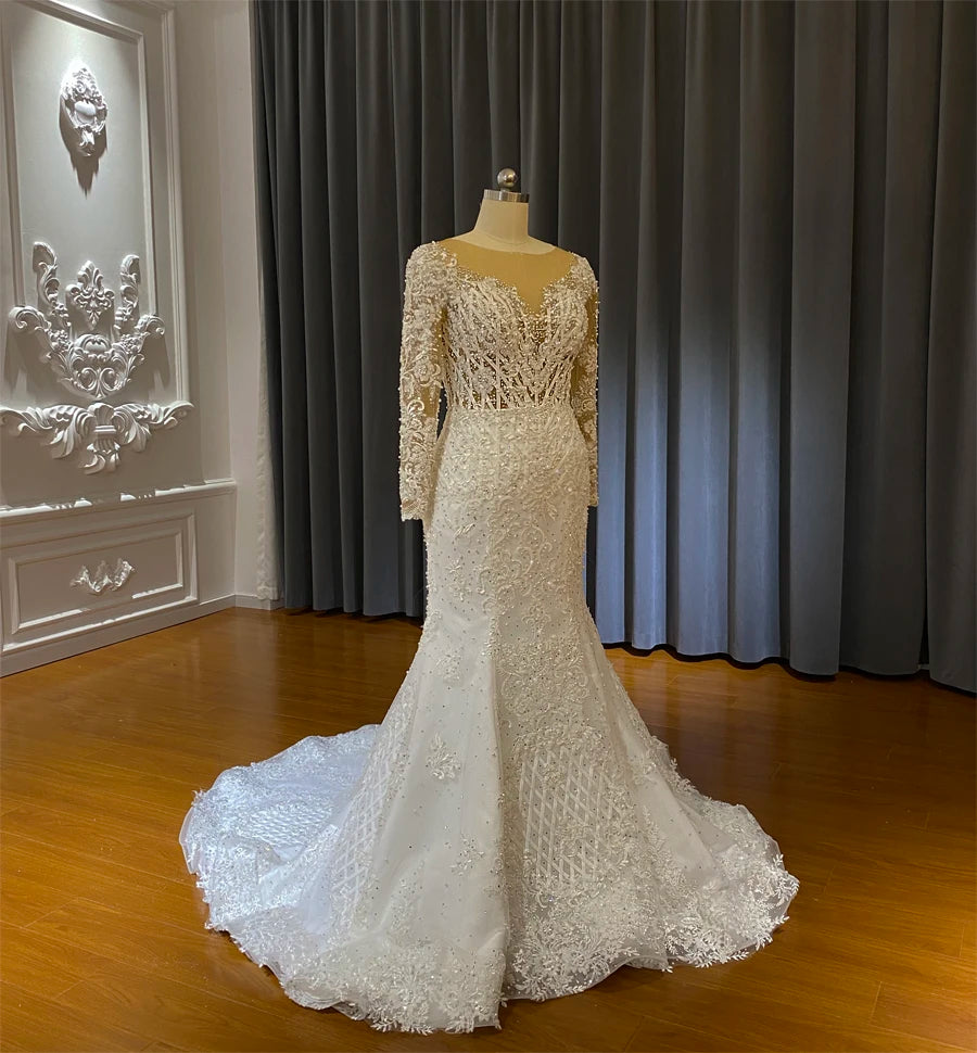 Mannequin-displayed long-sleeved beaded mermaid bridal gown from a side perspective, highlighting the fit-and-flare design.