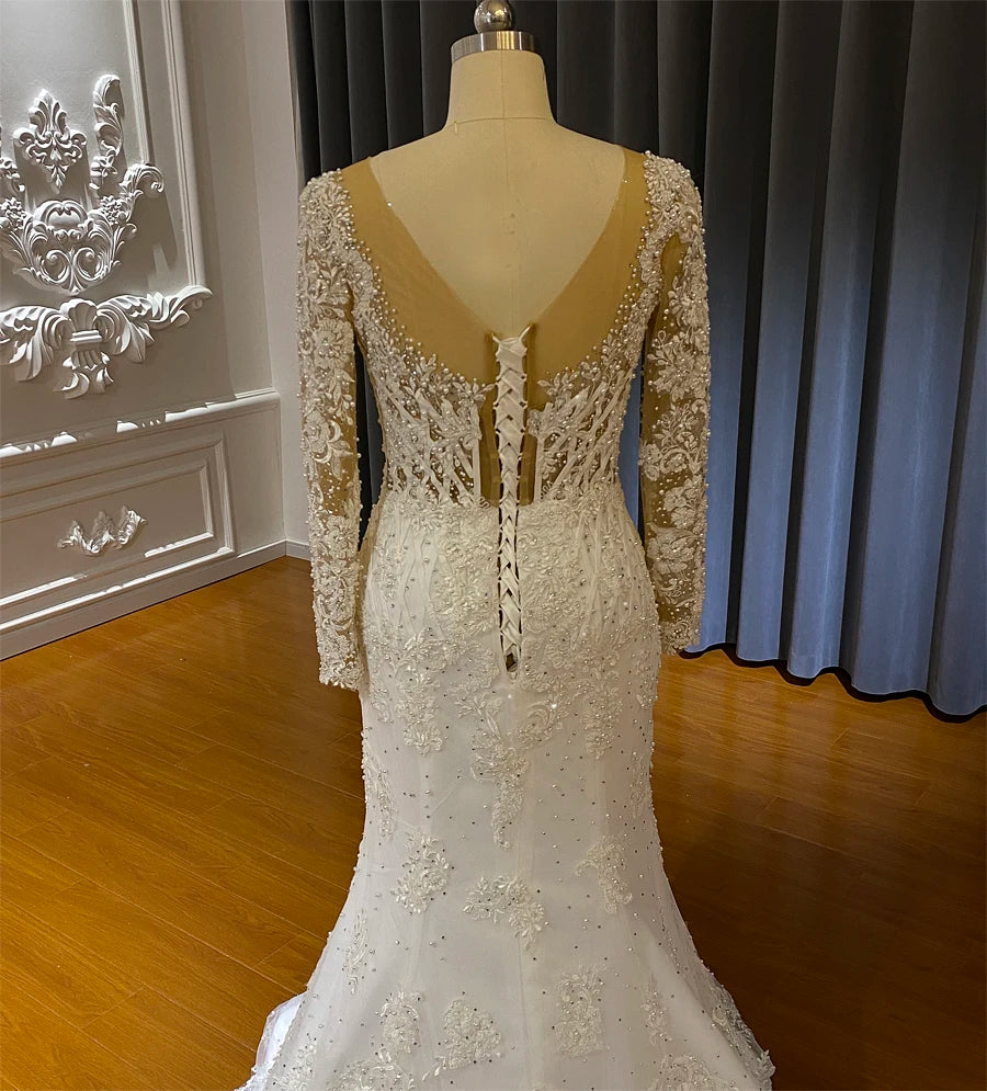 Detailed back view of a mermaid wedding dress featuring a corset lace-up closure and sheer beaded long sleeves.