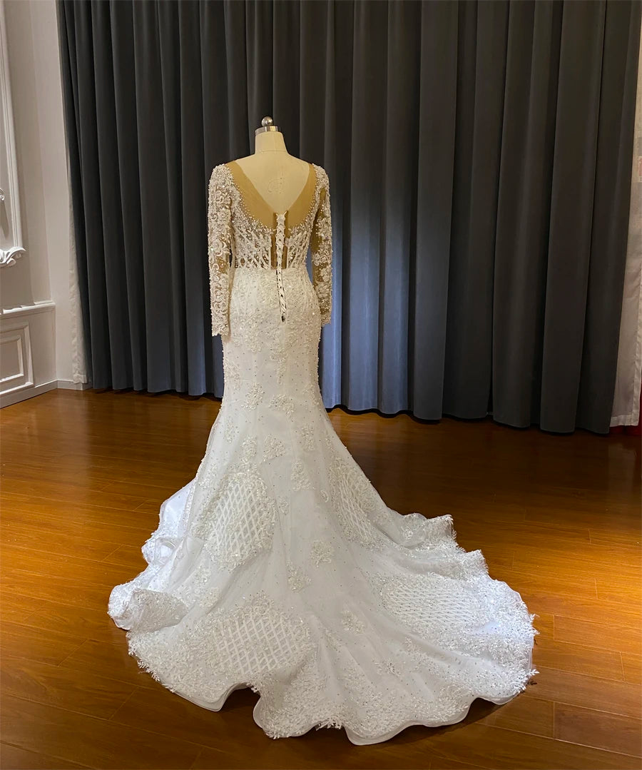 Full rear view of a white mermaid wedding gown on a mannequin, emphasizing the expansive lace train and V-back design.