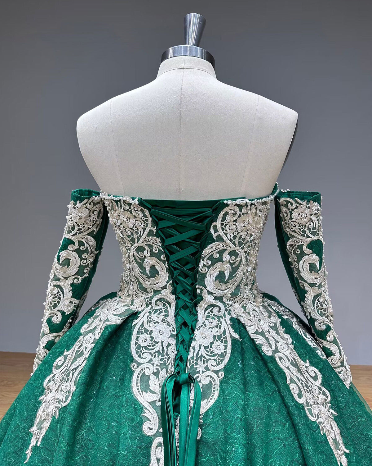 Symmetrical direct back view of the green quinceanera dress bodice highlighting the classic adjustable satin tie closure and ornate silver embroidery.