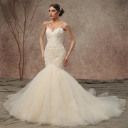 Front view of a model wearing a beaded lace mermaid wedding dress with spaghetti straps and a voluminous flared tulle skirt.