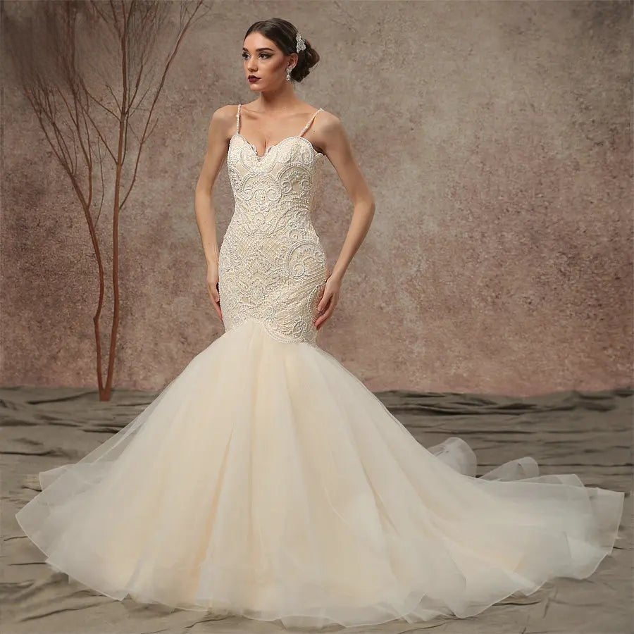 Front view of a model wearing a beaded lace mermaid wedding dress with spaghetti straps and a voluminous flared tulle skirt.