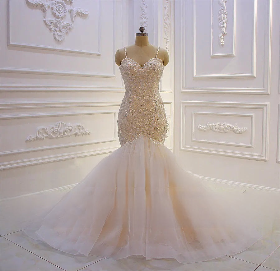 Full-length front view of a beaded lace mermaid wedding dress with spaghetti straps and a champagne-toned bodice on a mannequin.