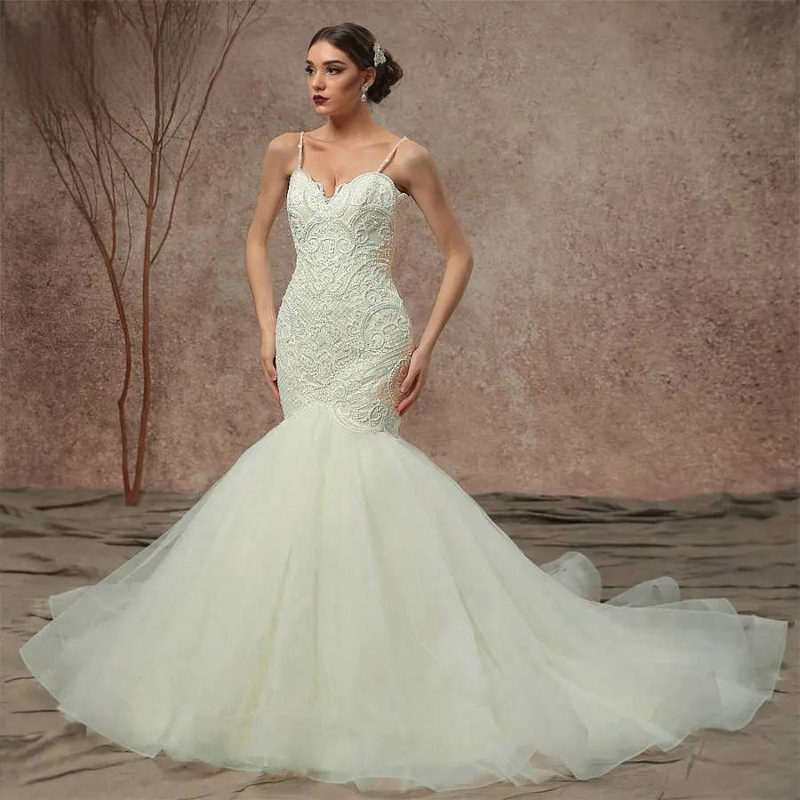 Stunning model posing in a champagne beaded lace mermaid wedding dress with delicate spaghetti straps and a dramatic tulle skirt.