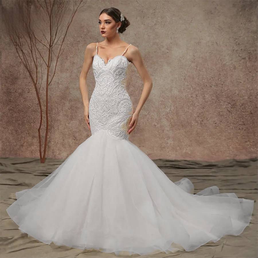 Front view of a model wearing an elegant white mermaid wedding dress featuring an intricately beaded lace bodice, delicate spaghetti straps, and a dramatic flared tulle skirt.