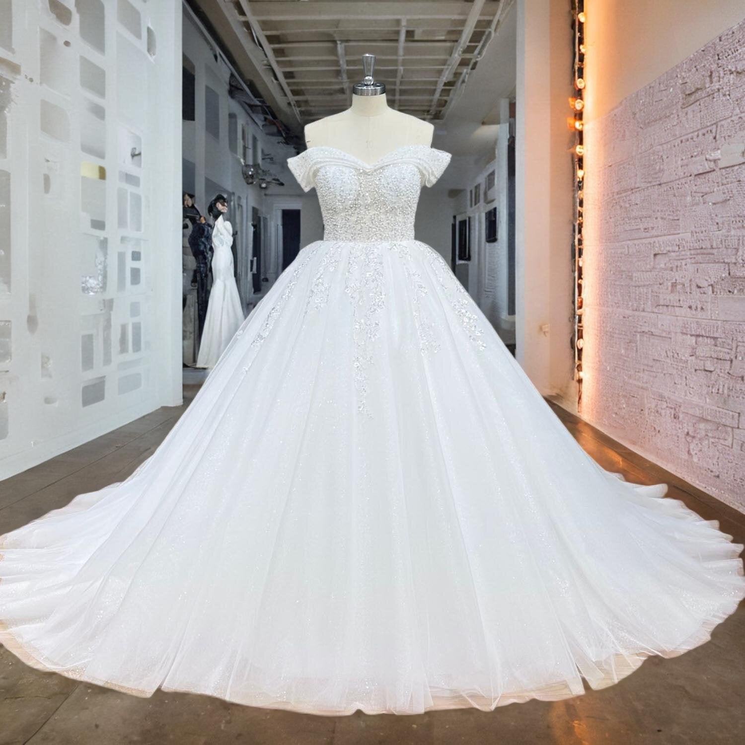 Full-length front view of an elegant off shoulder ball gown wedding dress with a beaded pearl bodice on a mannequin.