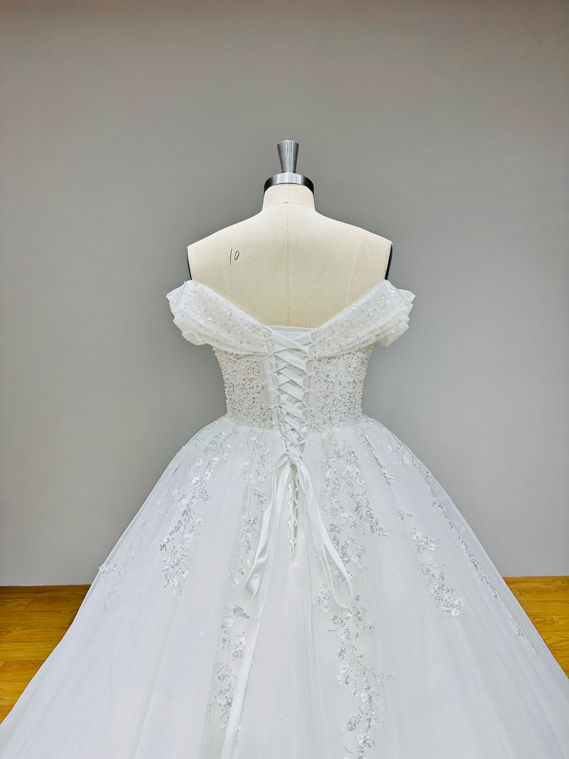 Close-up detail of the hand-beaded and pearl-embellished bodice on an off shoulder bridal ball gown.