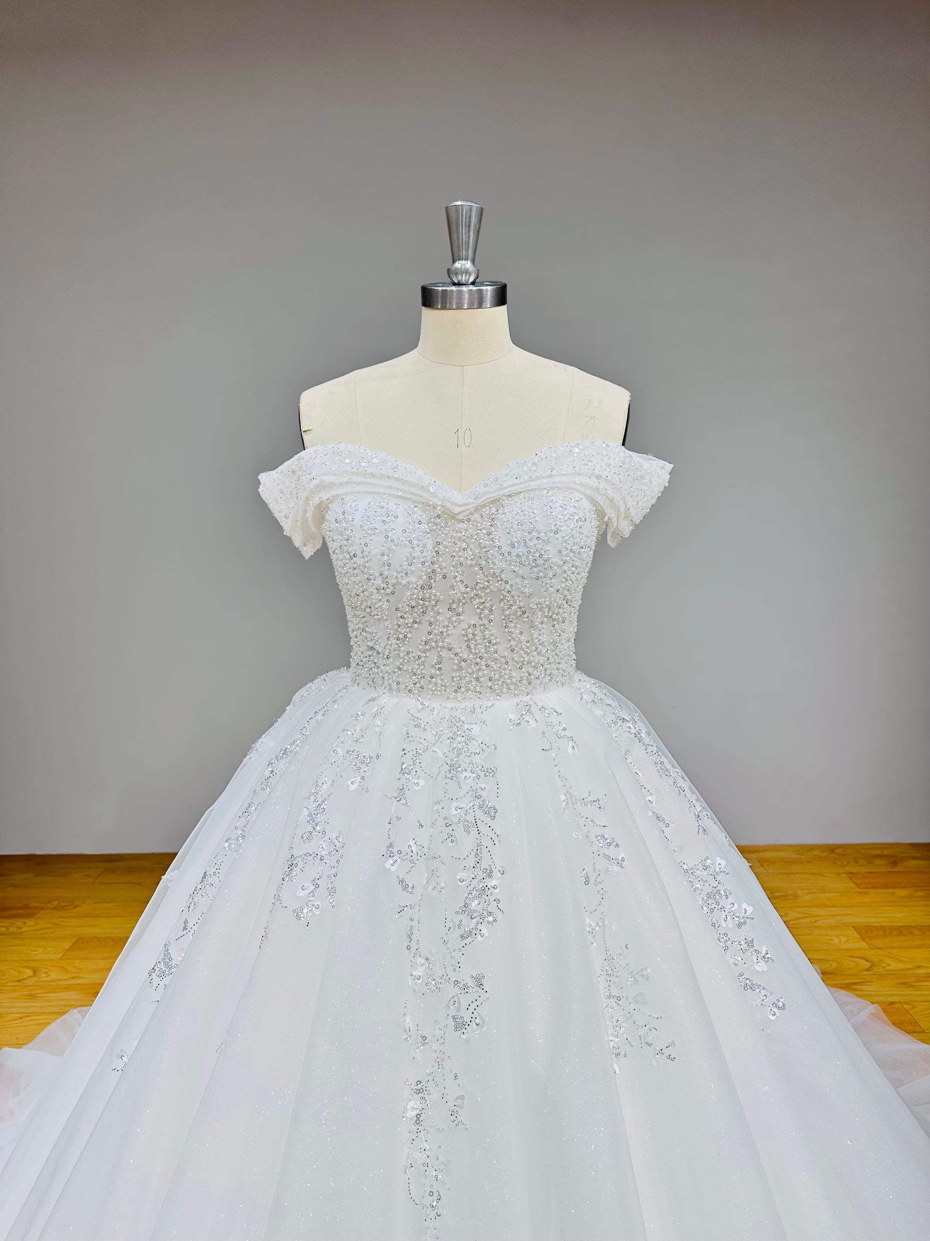 Full-length front view of a luxury off shoulder bridal ball gown with a dramatic train and lace up back closure.
