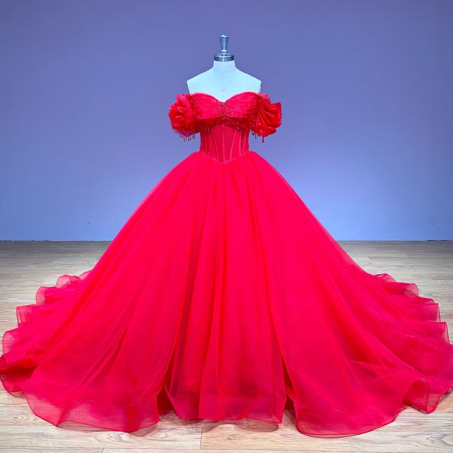 Full front studio product view of the red off-the-shoulder special event ball gown with a voluminous layered tulle skirt displayed on a mannequin.