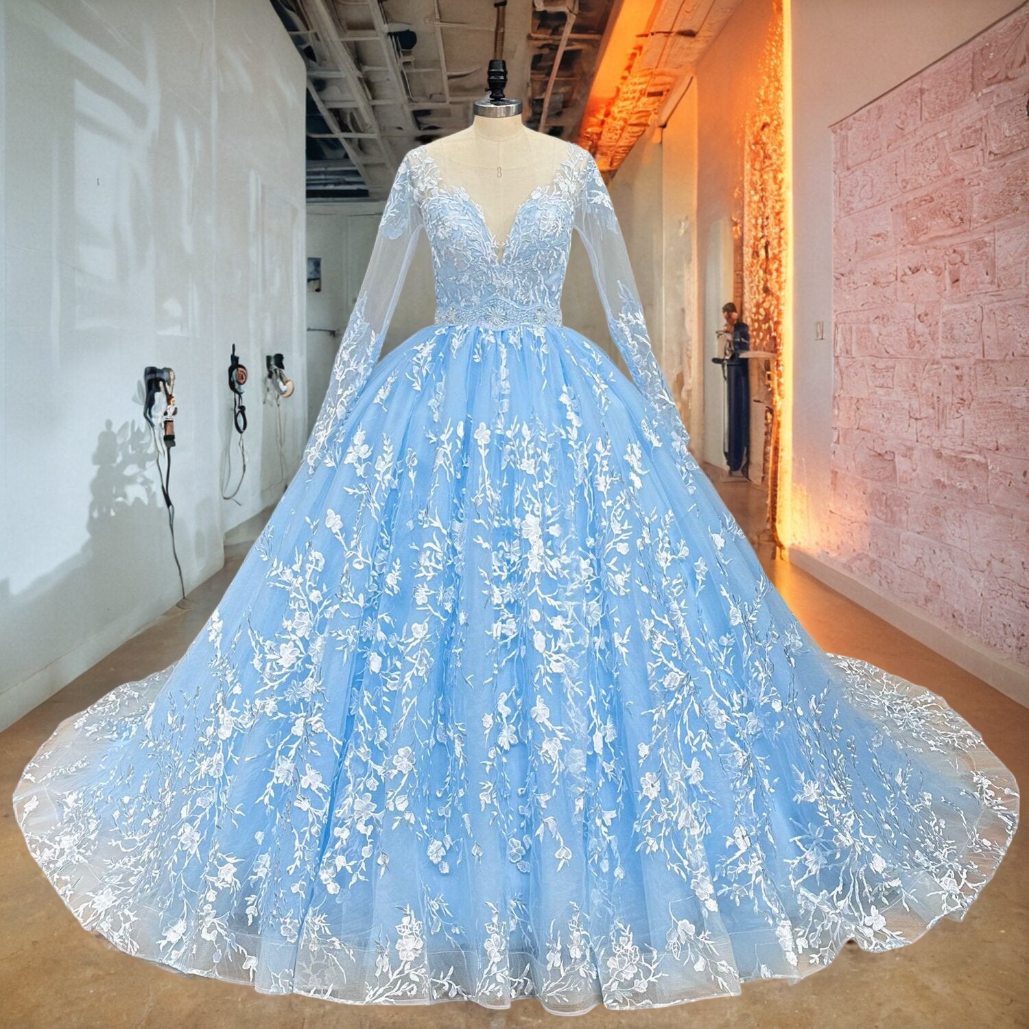 Ice blue long-sleeve princess wedding dress with dense white lace appliques and a glittering beaded waistband displayed on a mannequin in a showroom.