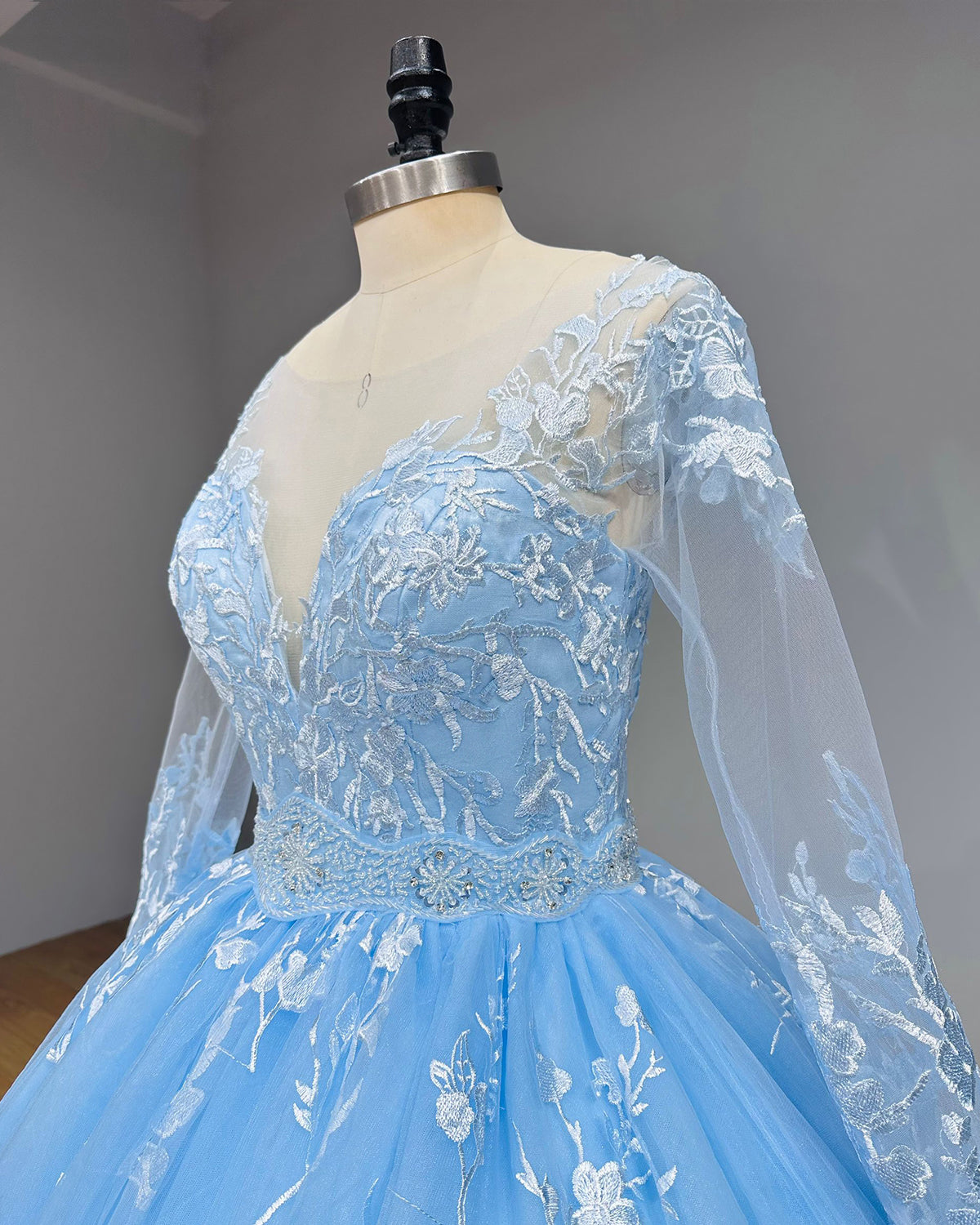Side angle close-up of a sky blue wedding dress bodice showcasing the texture of the white floral lace embroidery and shimmering sequin details.