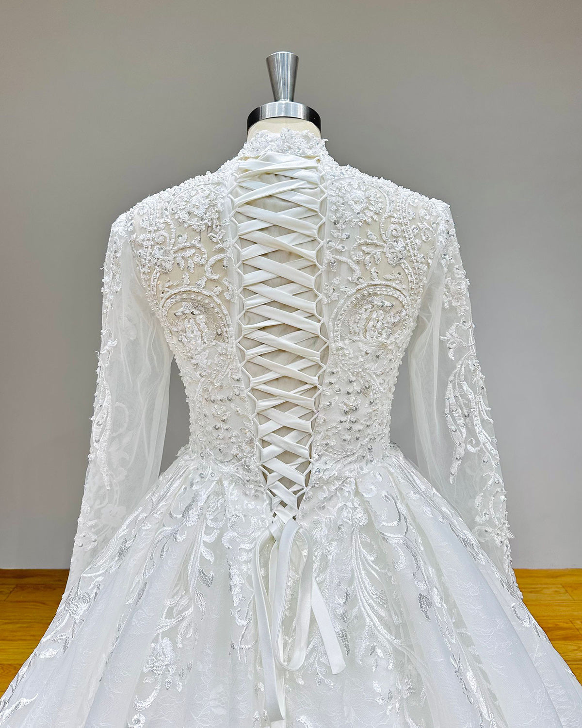 Close-up front bodice view of a new high neck ball gown wedding dress on a mannequin, emphasizing the sheer illusion neckline, structured sweetheart underlay, and dense beaded pearls.