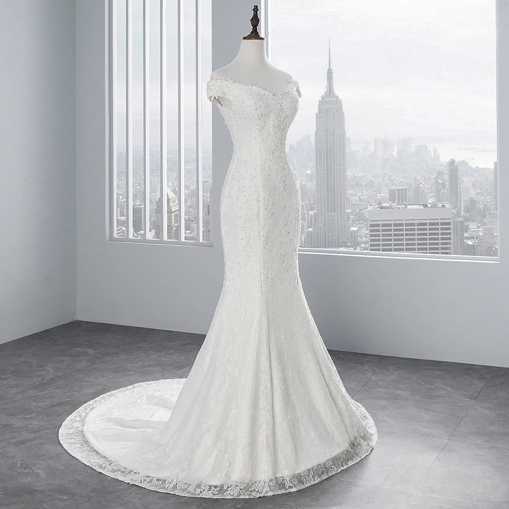 Full-length view of a white off-shoulder mermaid wedding dress on a mannequin, set against a backdrop of a city skyline.