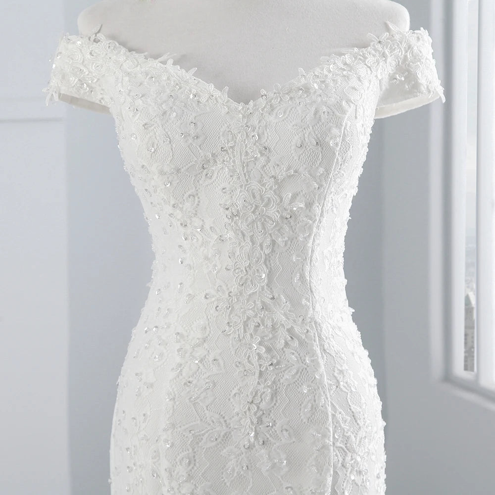 Detailed close-up of the elegant off-shoulder lace bodice and delicate beadwork on a mermaid bridal gown.