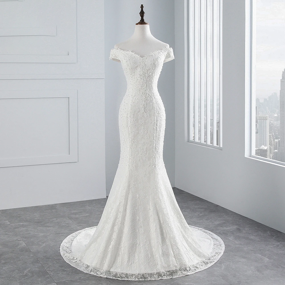 A mannequin displaying the classic off-shoulder mermaid wedding dress with a focus on the fitted bodice and flowing lace hem.