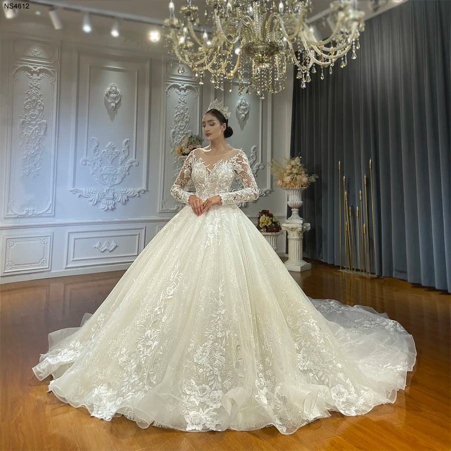 Full-length front view of a custom A-line wedding gown featuring shimmering floral embroidery and elegant long lace sleeves.