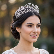Close-up portrait of a smiling bride wearing a new tiaras flower crown featuring an intricate silver floral vine pattern with sparkling crystals.
