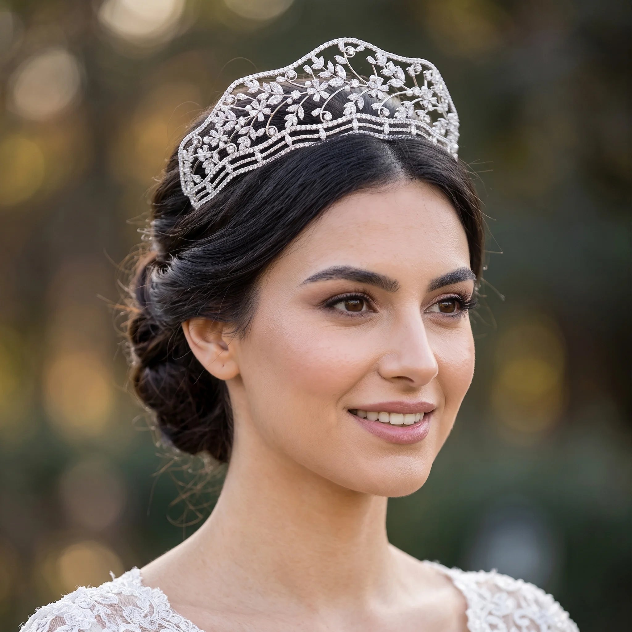 Close-up portrait of a smiling bride wearing a new tiaras flower crown featuring an intricate silver floral vine pattern with sparkling crystals.