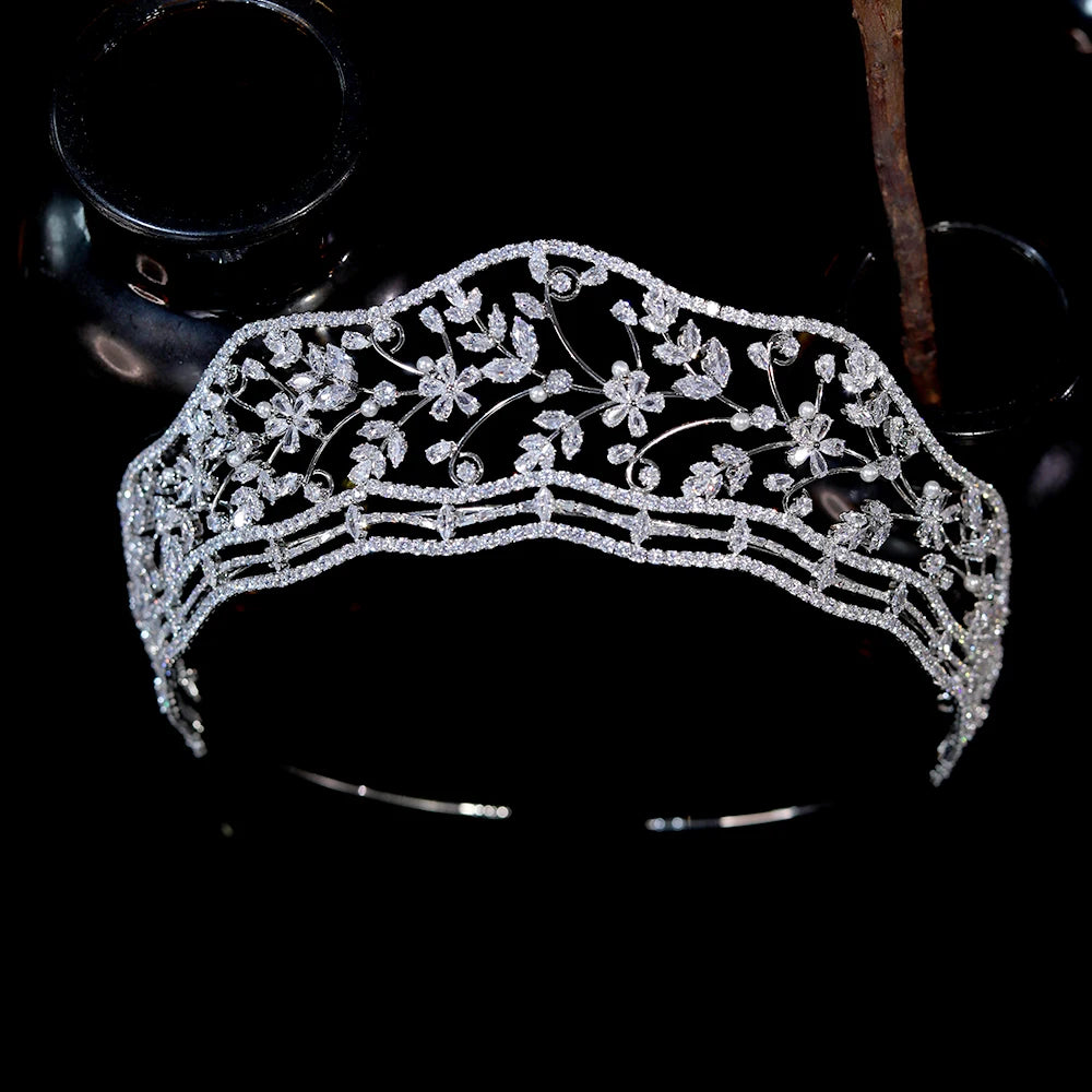 Symmetrical front-focused product shot of a silver cubic zirconia princess diara with botanical leaf patterns against a black reflective background.