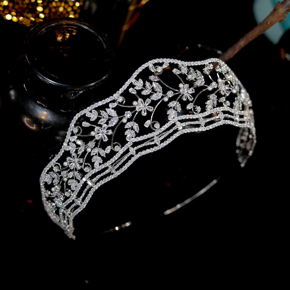 Perspective top-down look at the crystal vine bridal diadem tiara resting on a dark surface next to a decorative brown glass bottle.