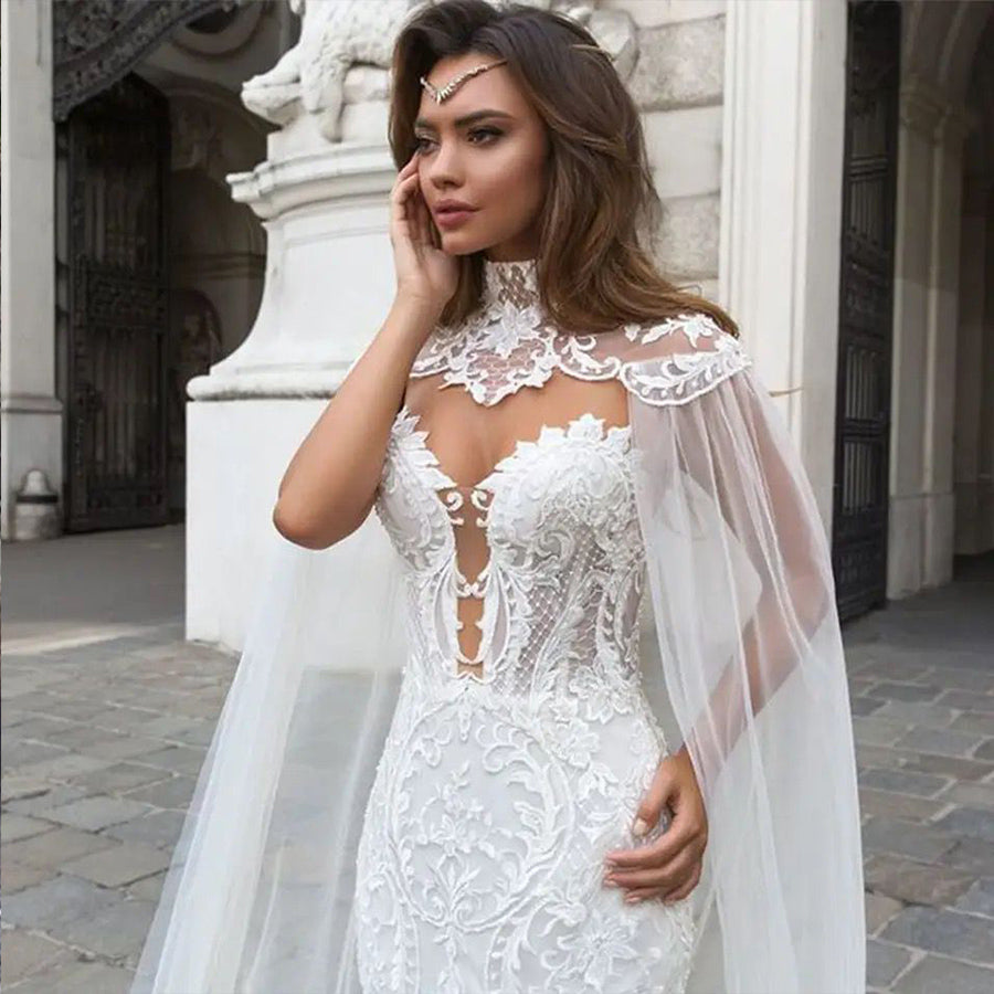 Close-up of a brunette bridal model wearing a mermaid wedding dress, highlighting the plunging sheer illusion sweetheart neckline and detailed high-lace collar cape.