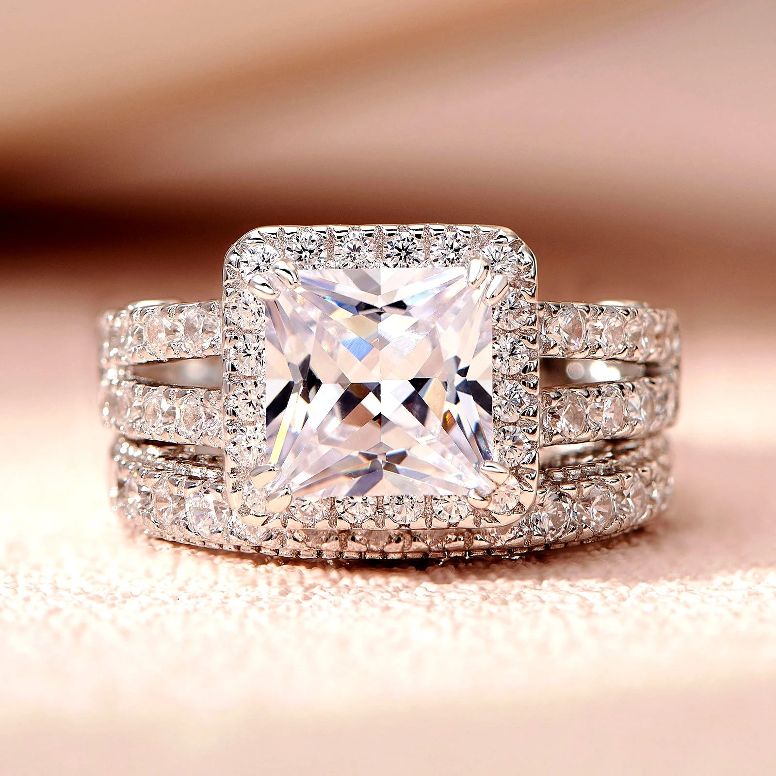 Straight-on studio macro photograph focusing on the geometric symmetry of the princess-cut stone and the halo border of the fine jewelry set.