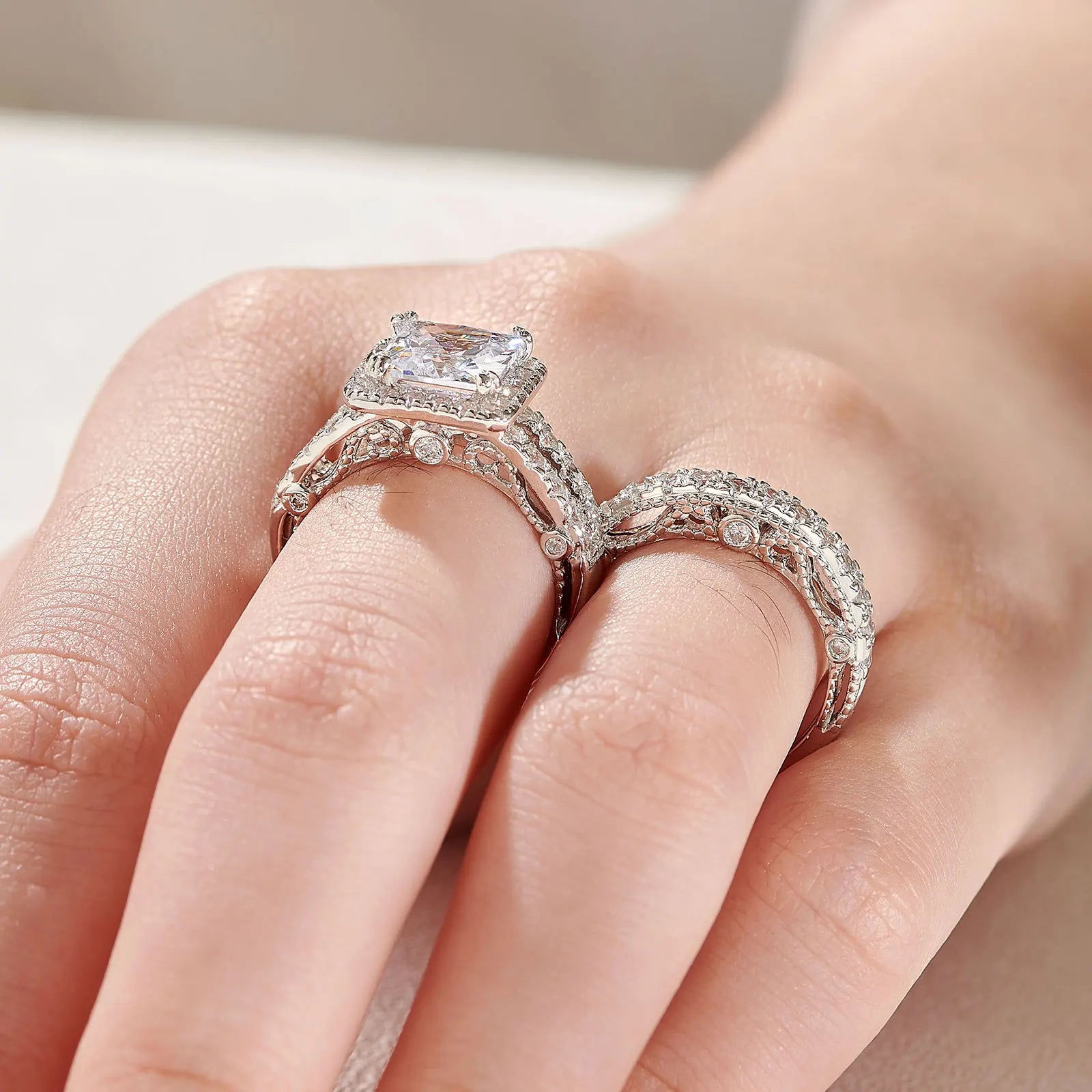 Side profile close-up of a women's silver wedding ring set on a finger, emphasizing the elevated halo crown setting and multi-row pave detailing.