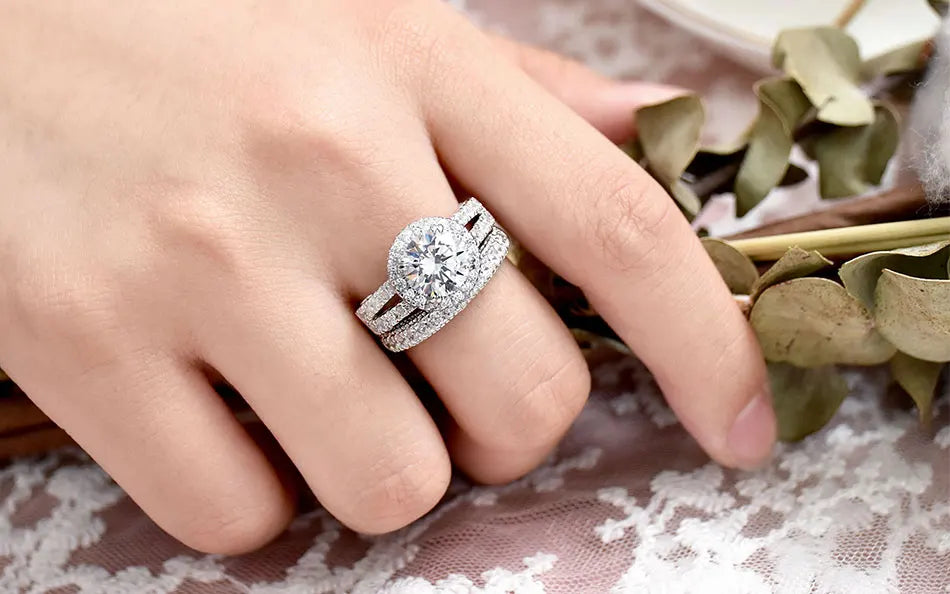 Classic round-cut brilliant cubic zircon halo bridal set in sterling silver presented gracefully on a woman's ring finger.