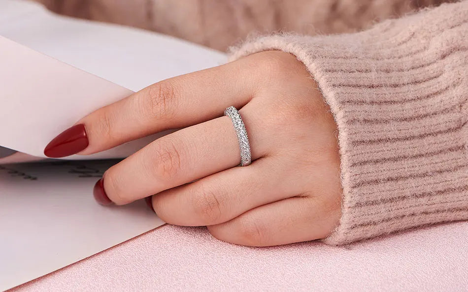 Close-up macro view of a classic sterling silver multi-row pave cubic zircon wedding eternity band worn solo on a finger.