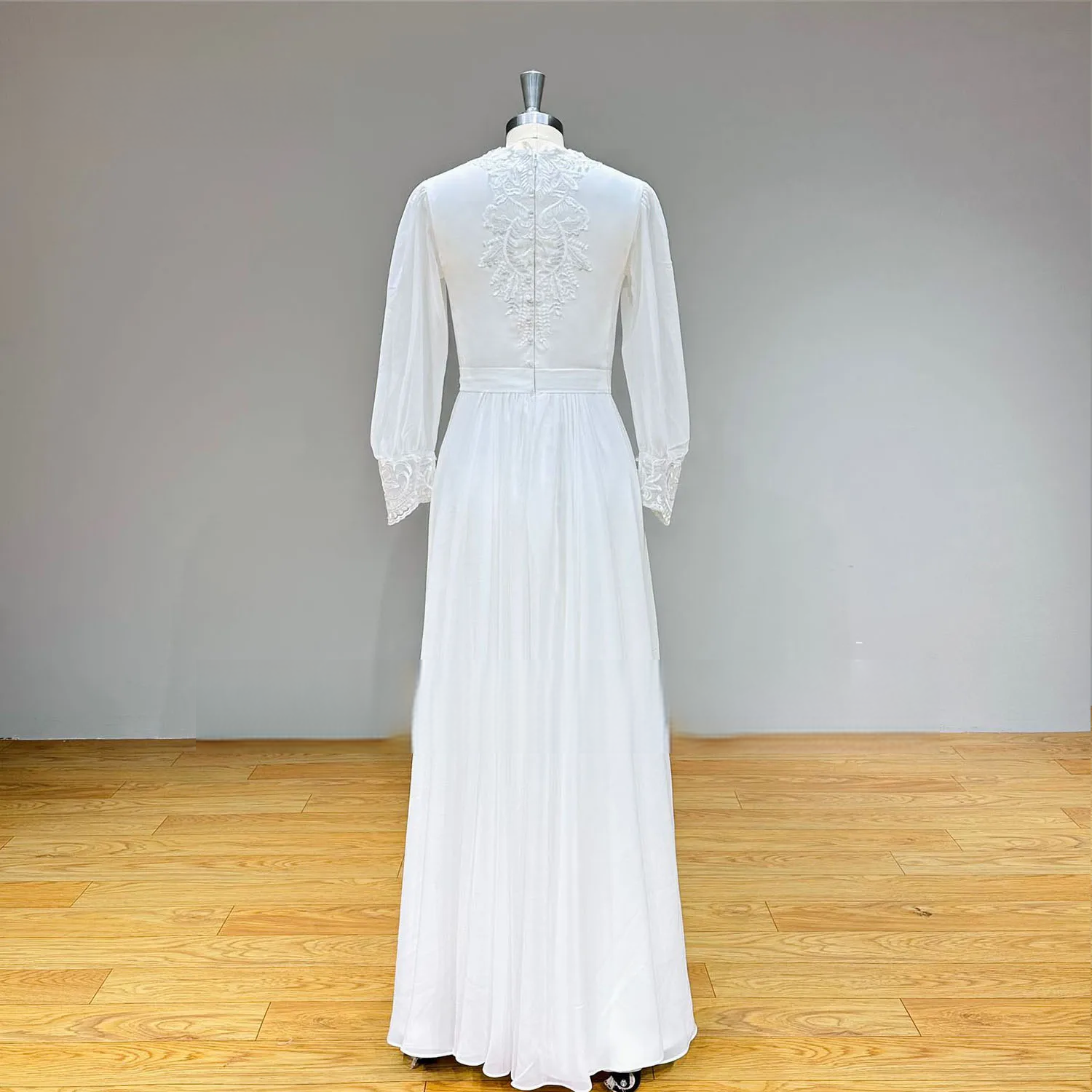 Rear view of the modest chiffon wedding dress on a mannequin, highlighting the elegant lace applique back design and the smooth, floor-length flow of the chiffon skirt.