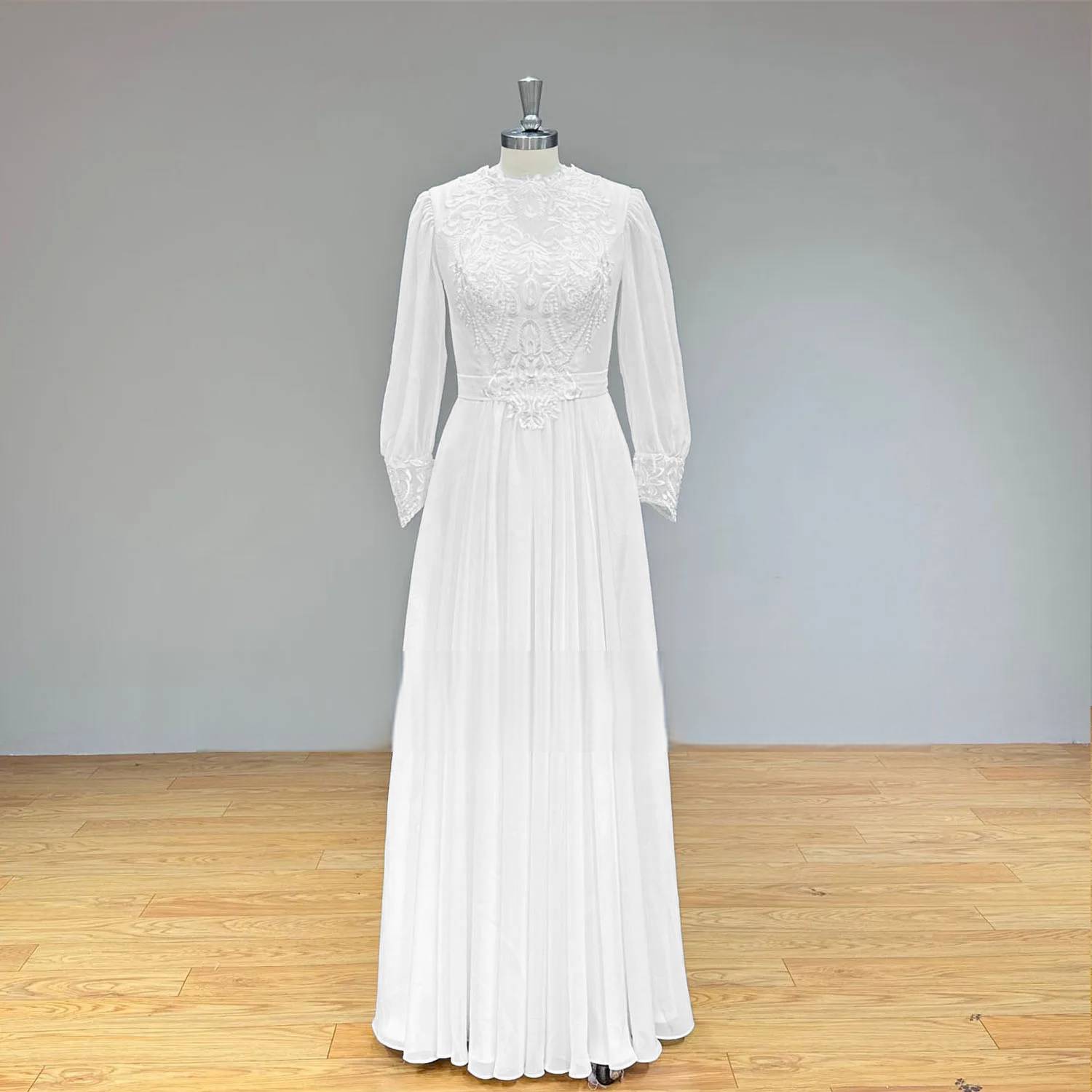 Studio front shot of a vintage-inspired long sleeve chiffon bridal gown on a mannequin, highlighting the elegant high neck and delicate floral lace embroidery.
