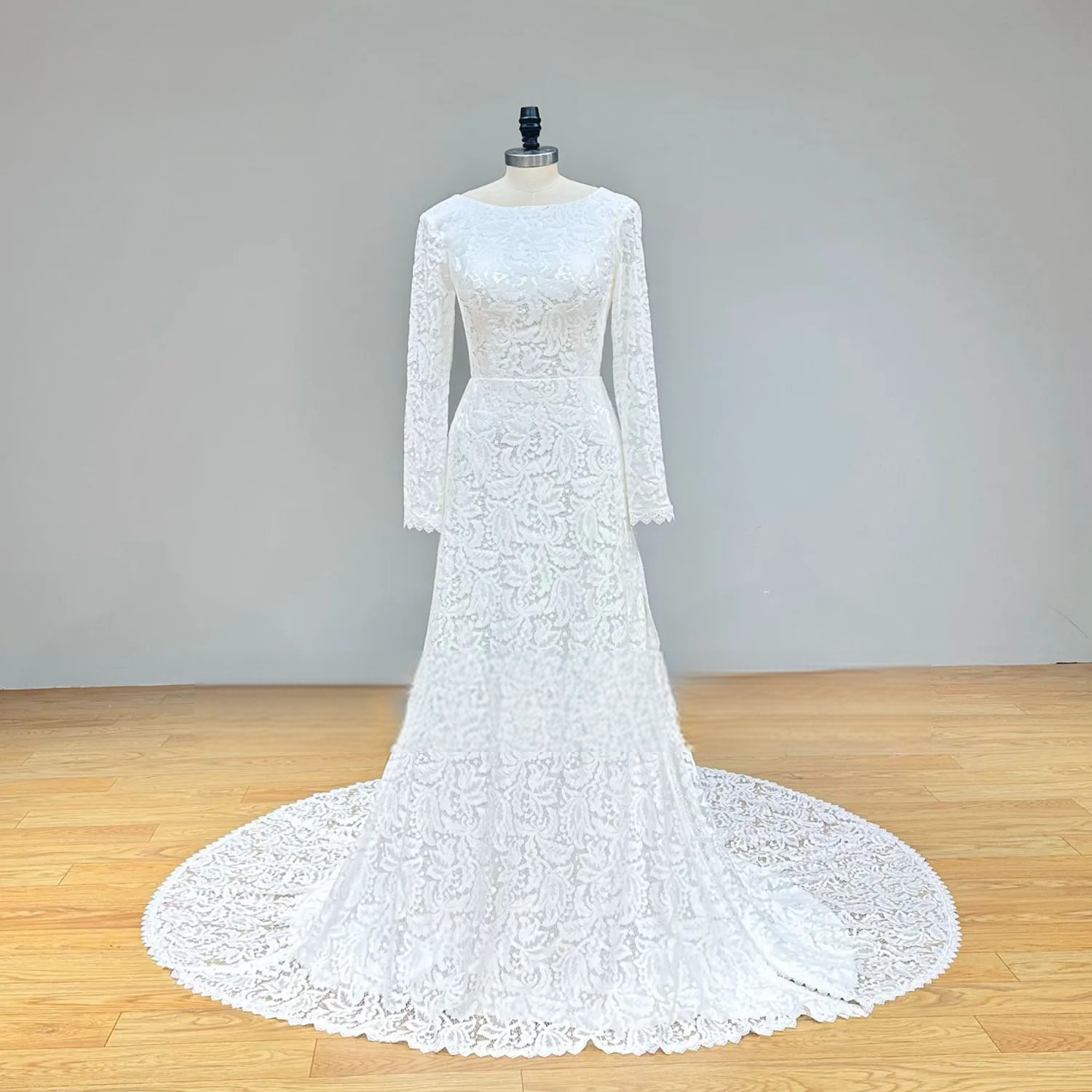 Full front perspective of a white all-over lace beach wedding dress on a mannequin, showcasing the long sleeves and elegant floor-length silhouette.