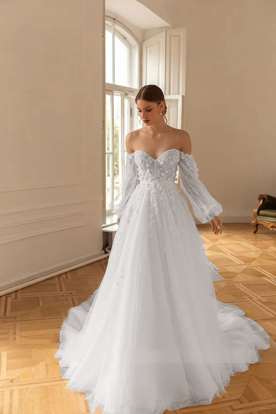 Full-length view of an off-shoulder A-line wedding gown with long sleeves, featuring floral lace details and a flowing tulle skirt.