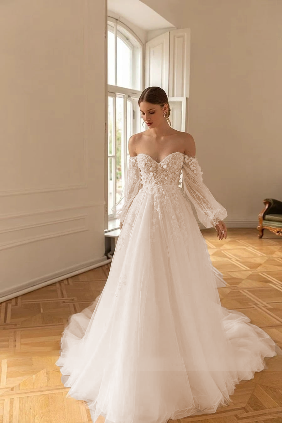 Editorial-style shot of a bride in an elegant off-shoulder A-line wedding gown, highlighting the sweetheart neckline and intricate long sleeves.