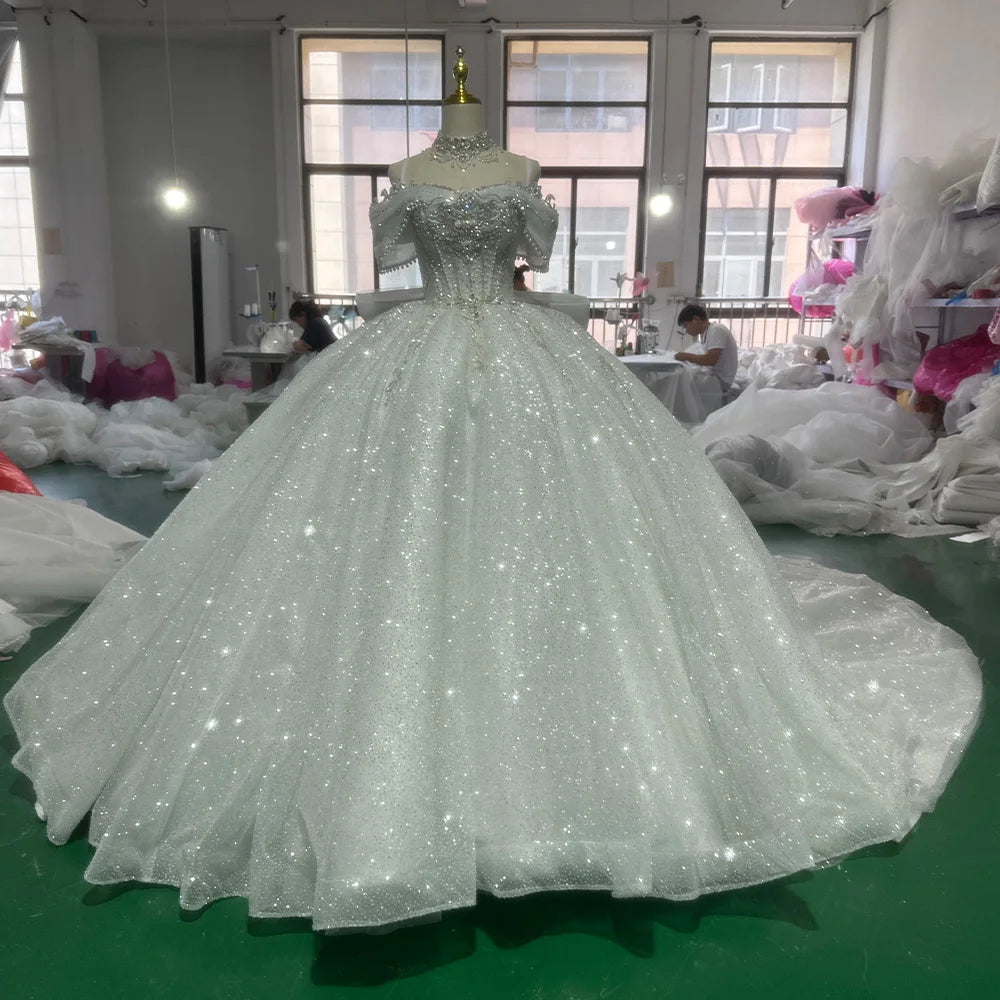 Showroom display of an off-shoulder beaded princess wedding dress on a mannequin, highlighting the sweetheart neckline and grand scale of the sparkling skirt.