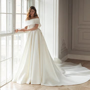 Minimalist satin A-line wedding dress featuring a structured off-the-shoulder boat neck portrait collar, tailored princess seams, and a high thigh slit skirt.