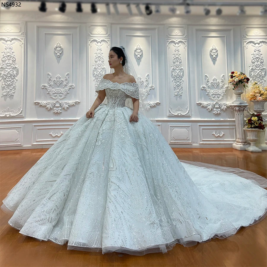 Full-length view of an elegant off-the-shoulder ball gown wedding dress with a shimmering bodice and voluminous full skirt.