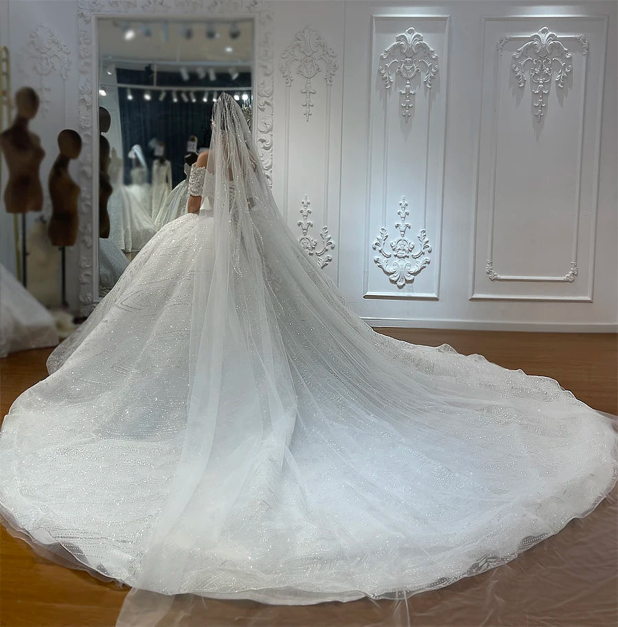 Back view of a sparkling wedding gown highlighting an expansive cathedral-length train and a long, matching glitter veil.