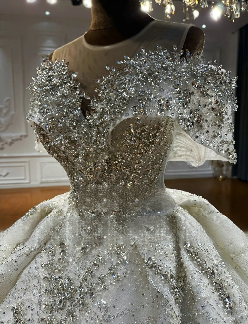 Close-up detail of the heavy crystal beadwork on the off-the-shoulder bodice and sheer illusion neckline of this luxury elegant wedding gown.