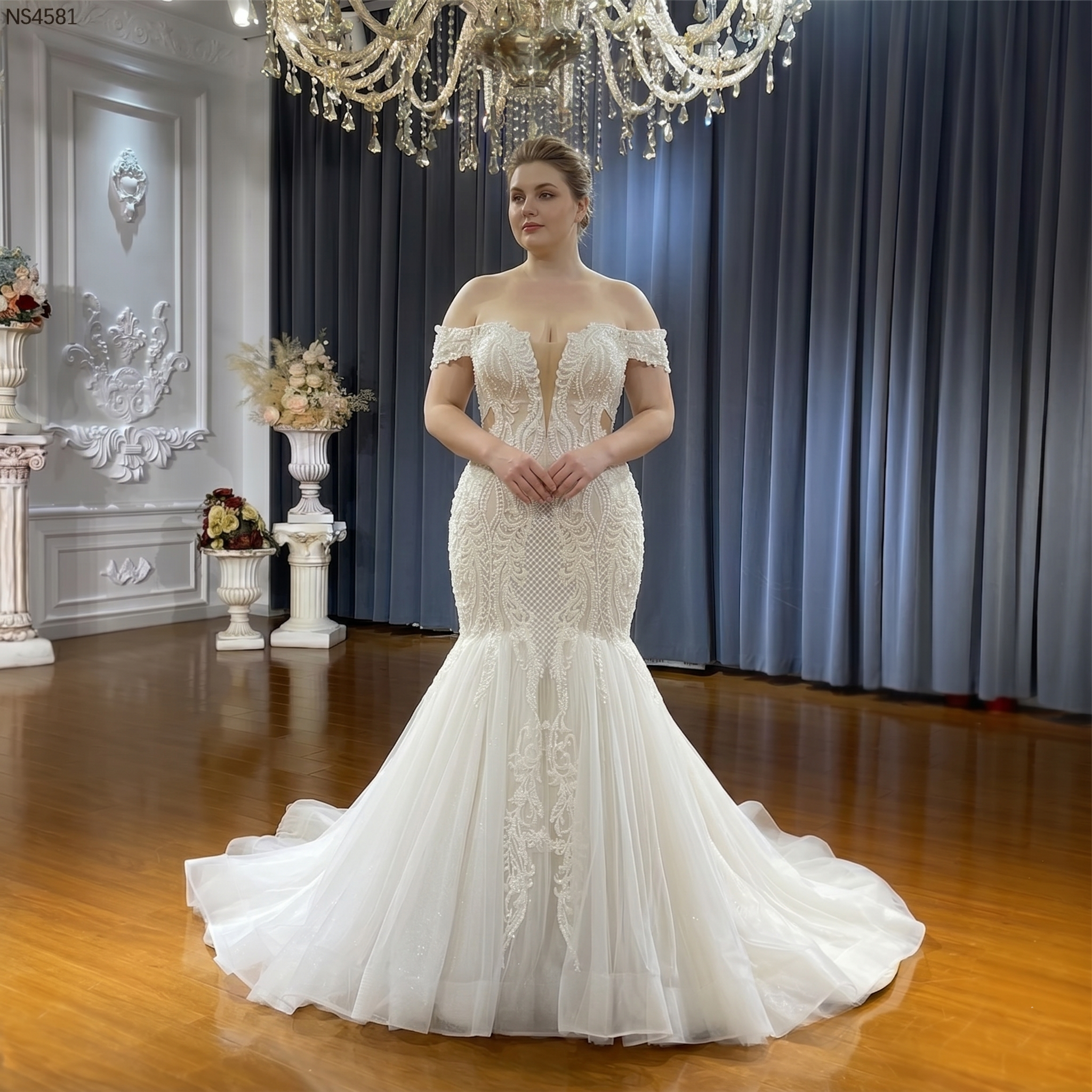A plus-size model wearing the stunning off-the-shoulder lace mermaid bridal gown, showcasing its flattering fit and flare silhouette.