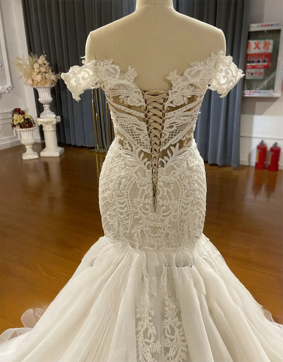Close-up shot of the back of the wedding gown, featuring a traditional lace-up corset closure and exquisite sheer lace detailing.