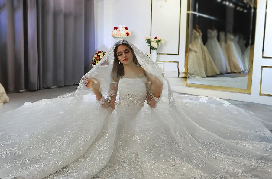 Romantic bridal portrait of a bride sitting in a lace wedding dress with an expansive embroidered veil spread beautifully on the floor.