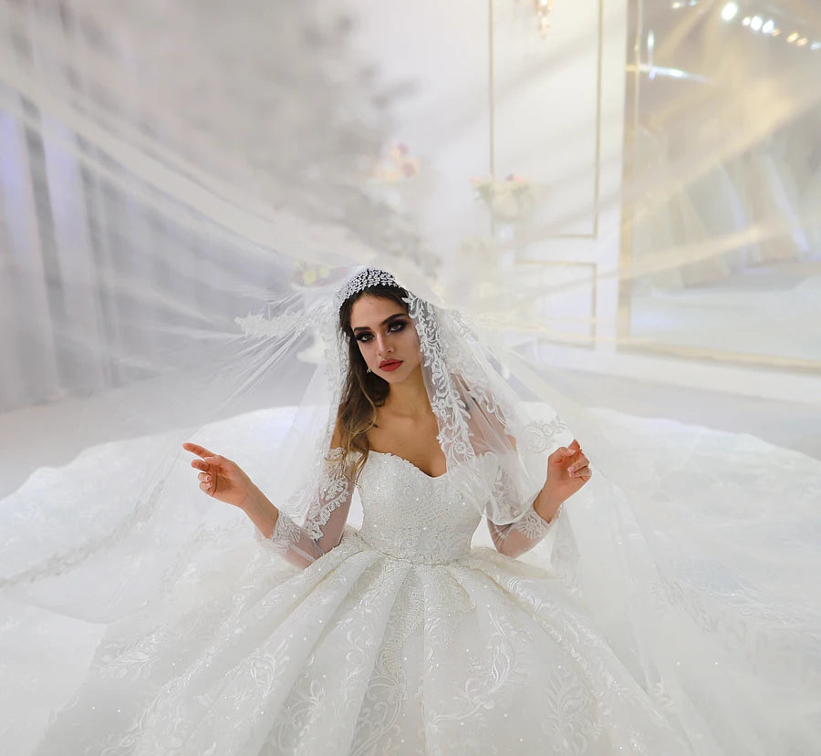 Close-up portrait of a bride wearing a lace-trimmed wedding veil and an off-the-shoulder bridal gown with intricate sequin detailing.