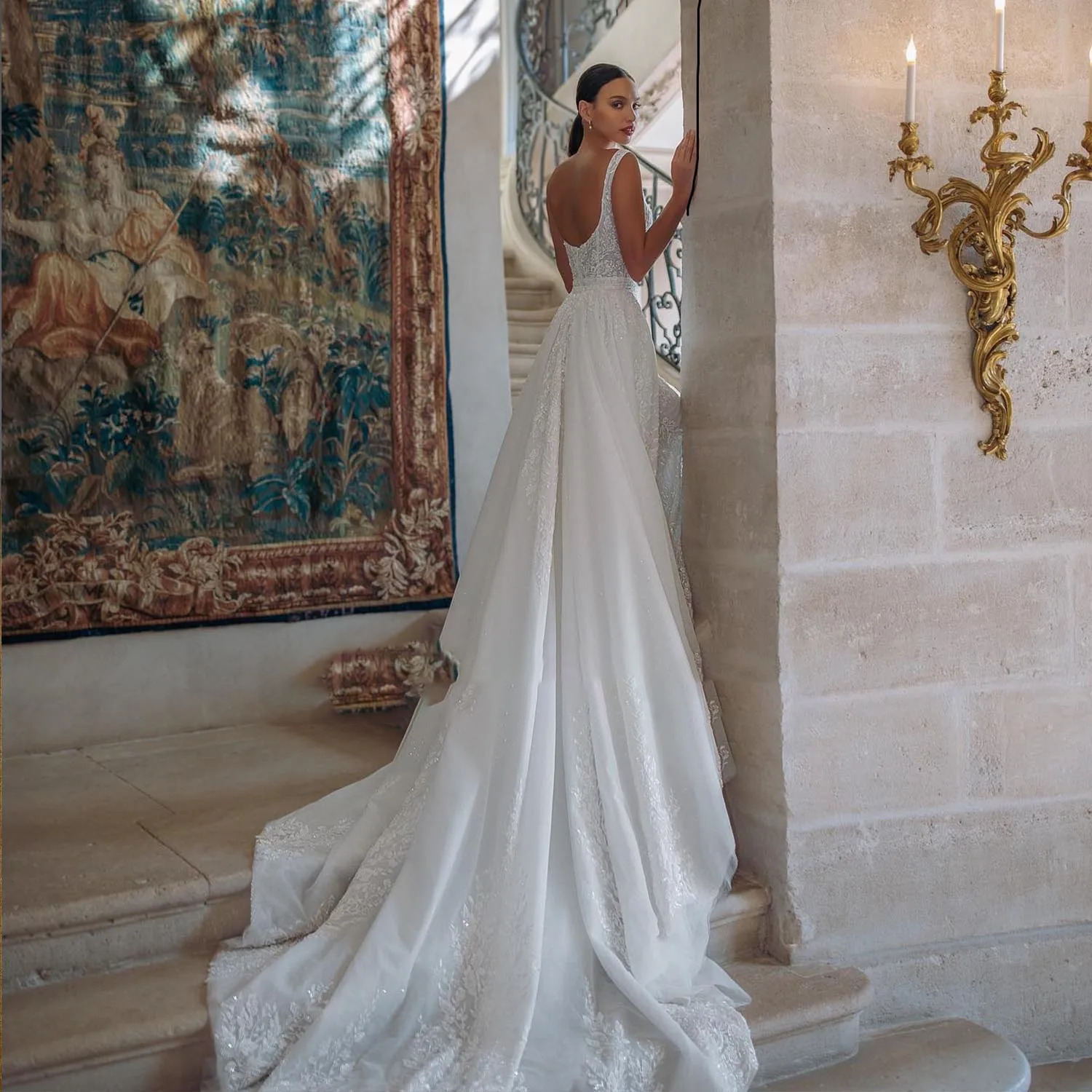 Full rear view of a luxury backless bridal gown featuring a grand, cascading detachable tulle cathedral train with embroidered lace borders.