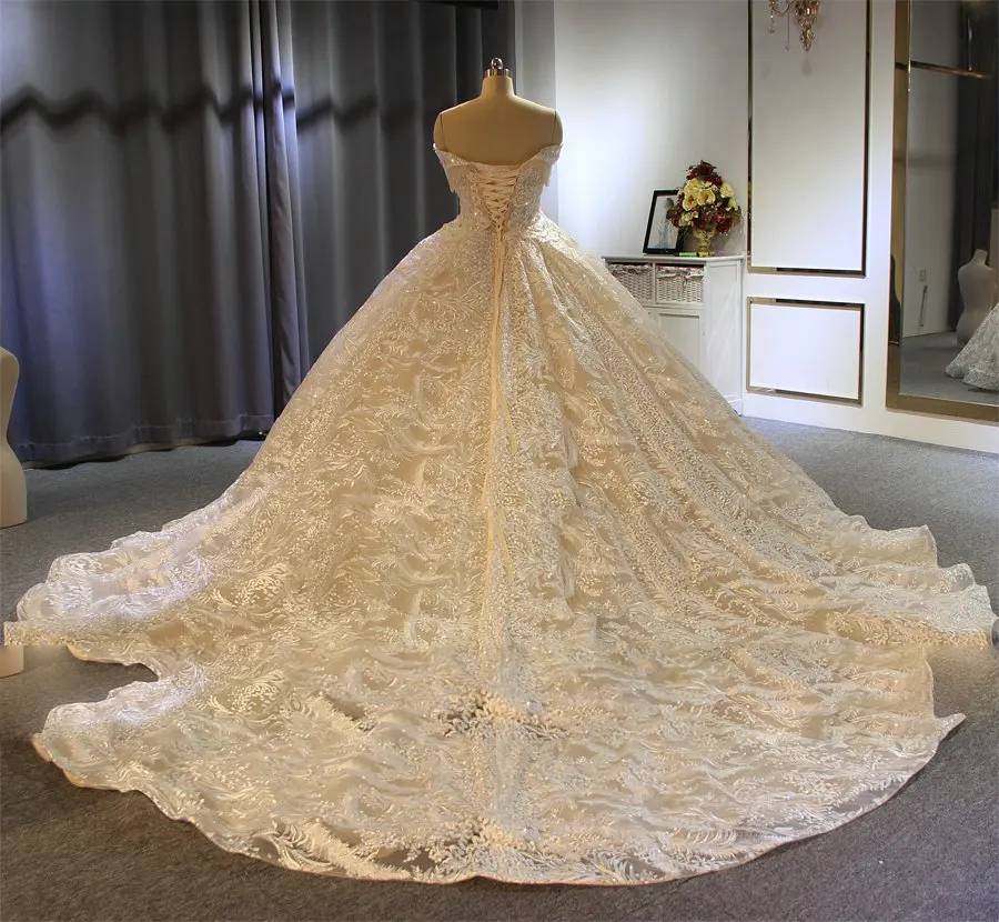 Back view of a heavily embellished ball gown wedding dress showing the lace-up corset back and wide cathedral-length train.