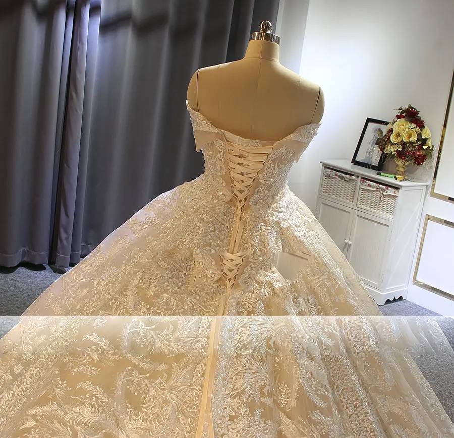 Close-up detail of a lace-up corset back on a luxury champagne ball gown bridal dress with intricate embroidery.