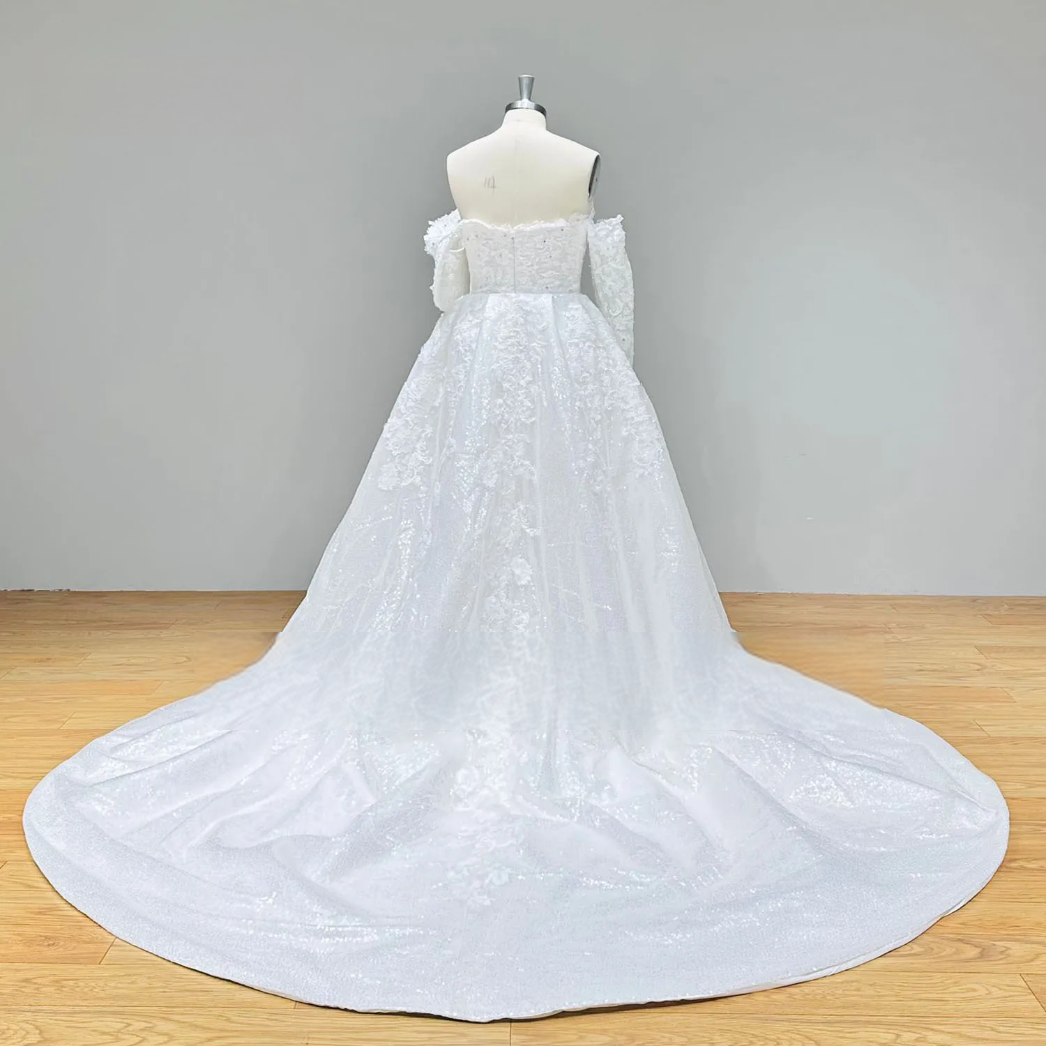 Rear full-length perspective of a mermaid wedding dress with its grand detachable cathedral train, emphasizing the expansive sweep and shimmering lace texture.