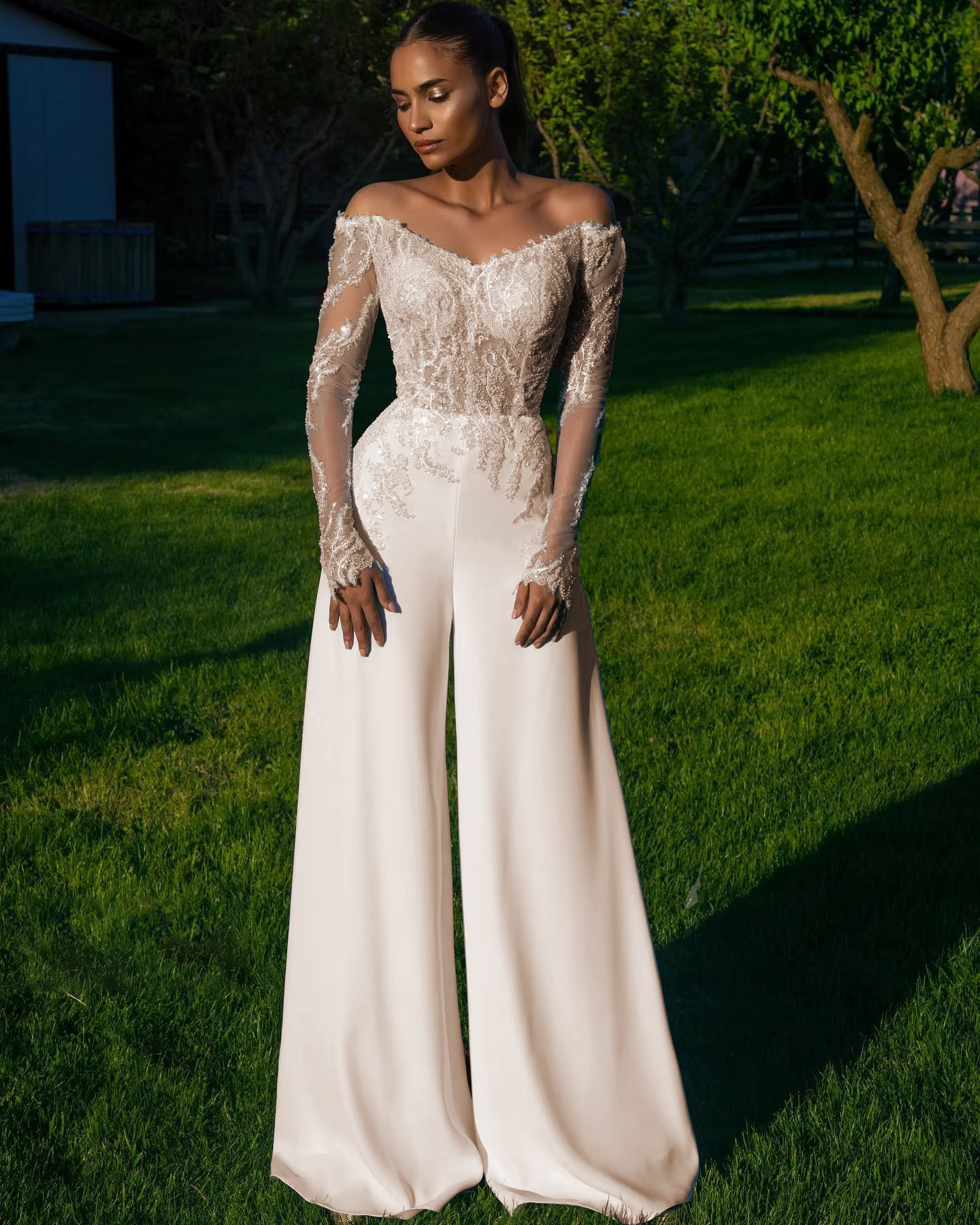 High-resolution front display of the off shoulder long sleeve wedding dress jumpsuit with a soft ivory finish, showcasing a modern alternative bridal gown silhouette.